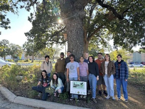 A group of people sit and stand under a large tree.