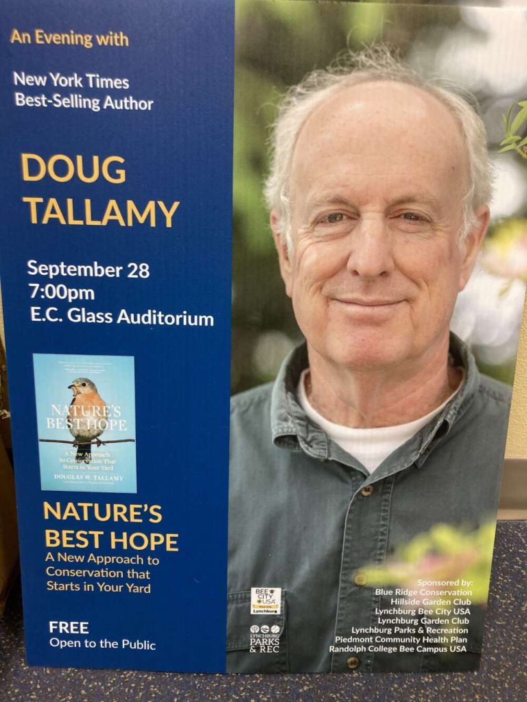 A photo of a poster with text and a person in a dark shirt smiling.
