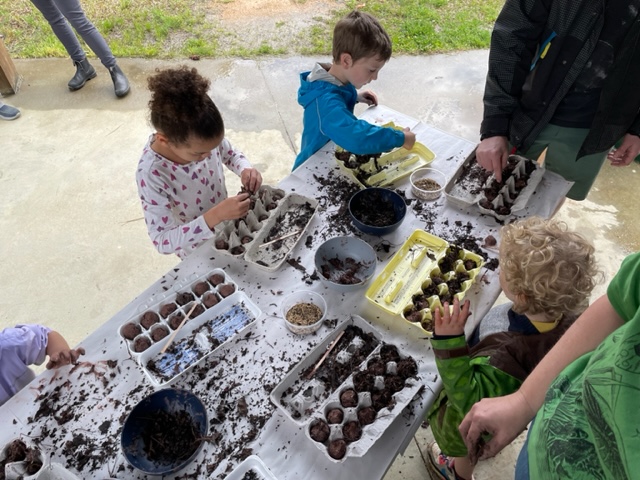 Children gathered at a table creating seed balls
