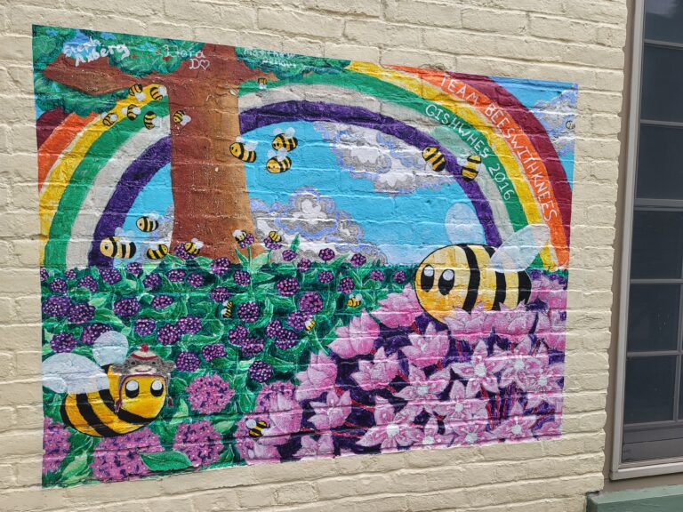 A cute mural of cartoonish bees with a rainbow and flowers.