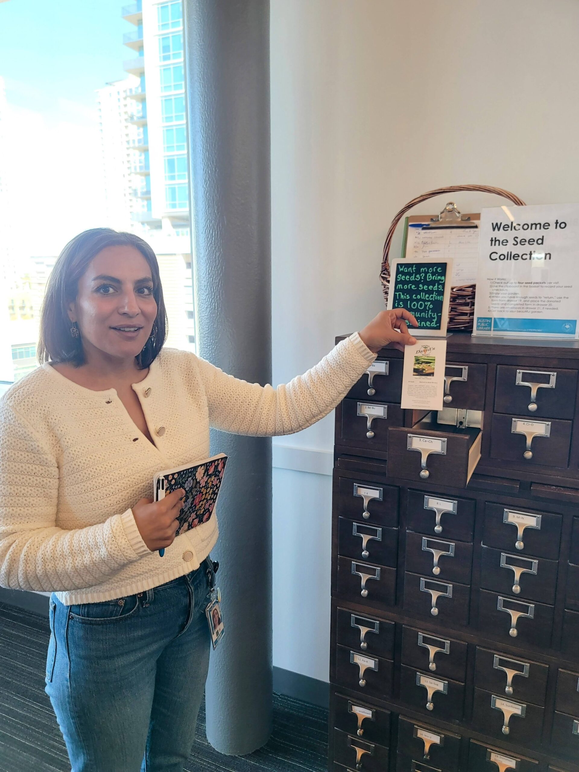 A person holds a seed packet next to a wood card catalog.