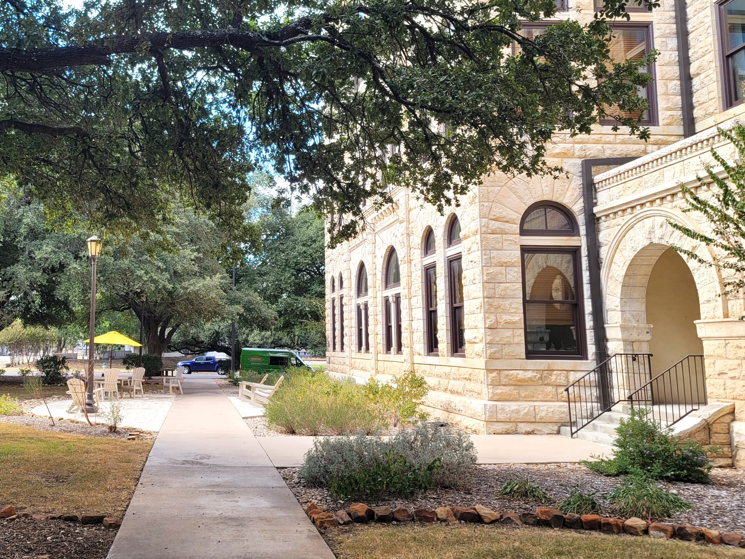 A nice stone building with a landscaped courtyard surrounded by oak trees.