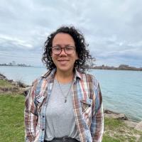 Picture of a smiling person in front of a shoreline.