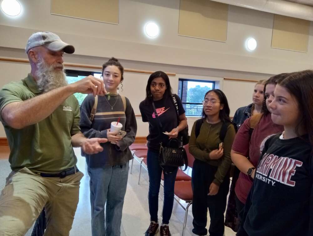 7 people look at a small object 1 person is holding up.