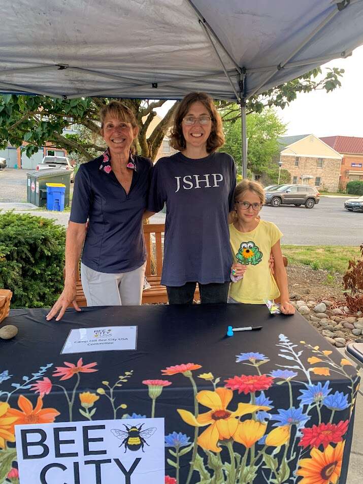 Two adults and a child smile behind a table at an event.