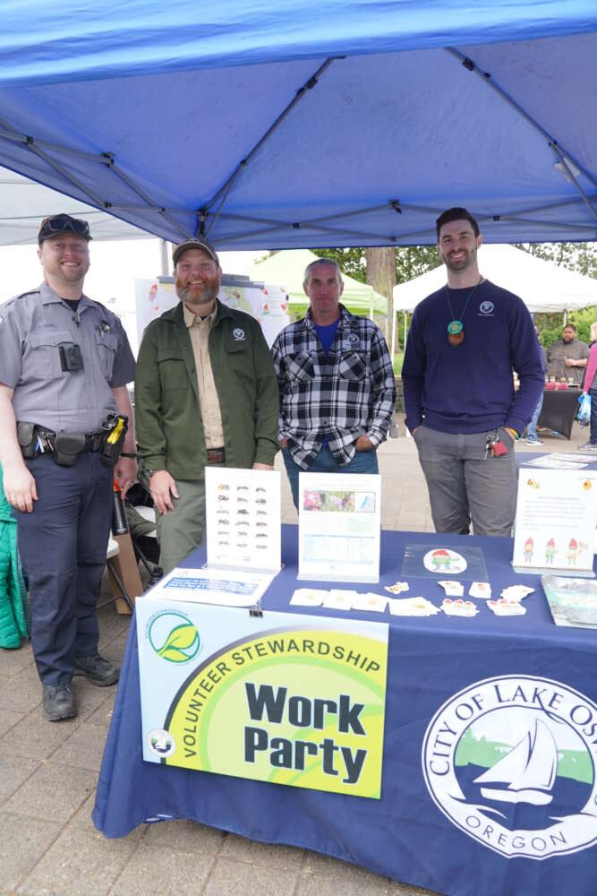Four people stand behind a table at an event.