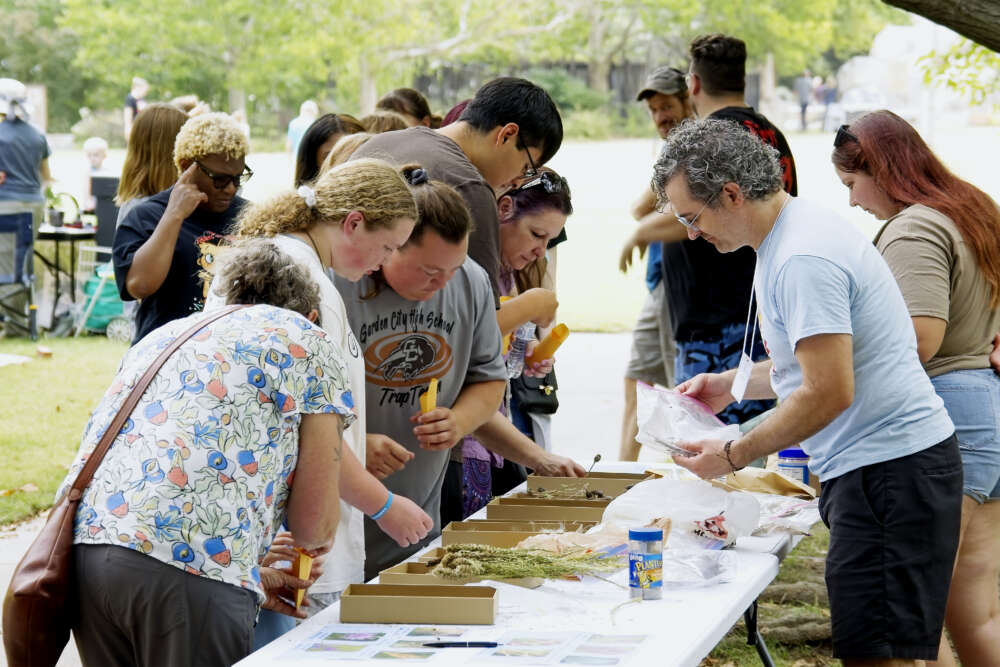 A large group of people look down at a table at an event.