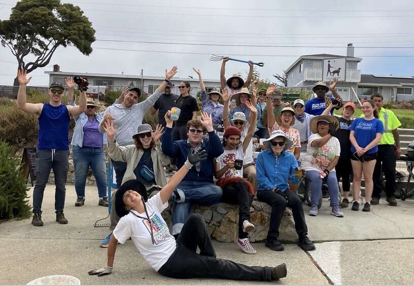 A group poses with their hands up