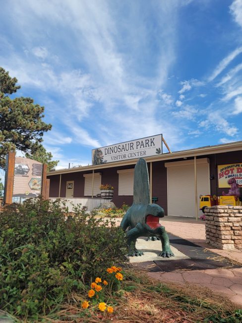 A green dinosaur statue next to a building.