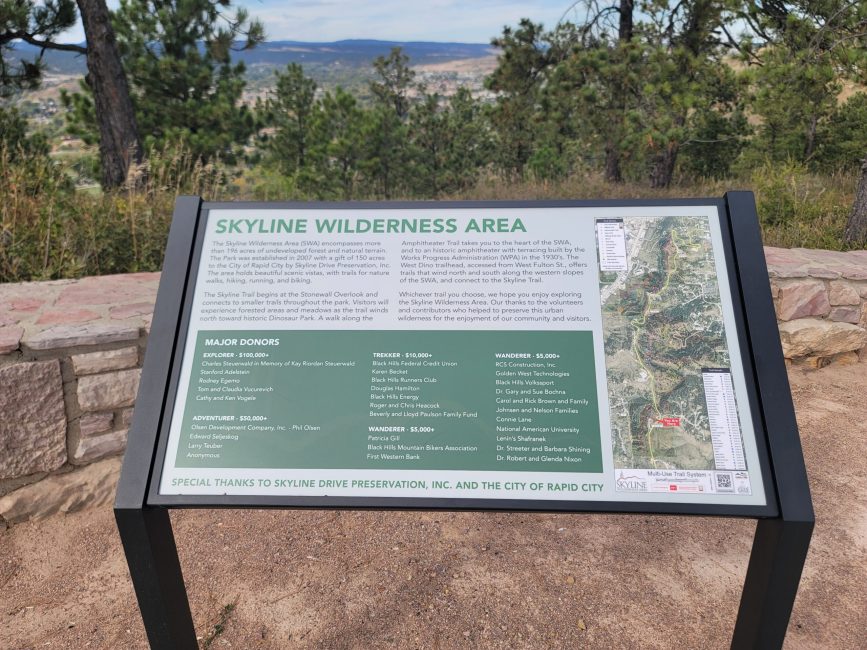 A white and green interpretive sign next to a viewpoint.