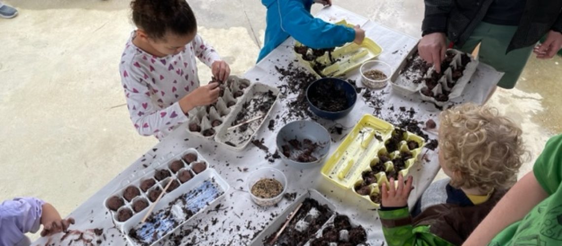 Children gathered at a table creating seed balls